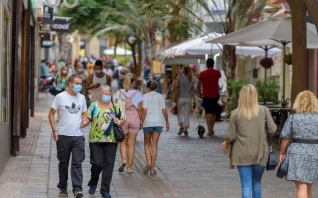 Personas paseando con mascarilla por una calle.