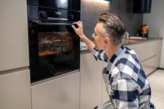 Un hombre programa un horno en su cocina.