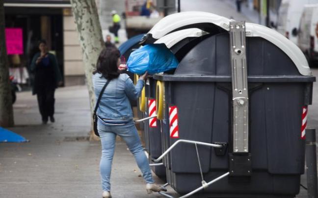 Una mujer -ajena a esta información- deposita una bolsa con residuos en un contenedor gris. Una mujer -ajena a esta información- deposita una bolsa con residuos en un contenedor gris.