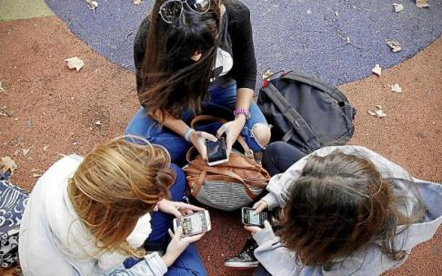 Varias menores se sientan juntas en un parque mientras utilizan sus móviles. Foto: Iban Aguinaga