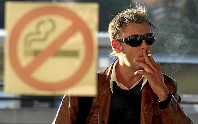Un hombre fuma ante un cartel que prohíbe esa práctica. Foto: N.G. Un hombre fuma ante un cartel que prohíbe esa práctica. Foto: N.G.
