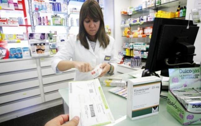 Una mujer despacha medicamentos en una farmacia.