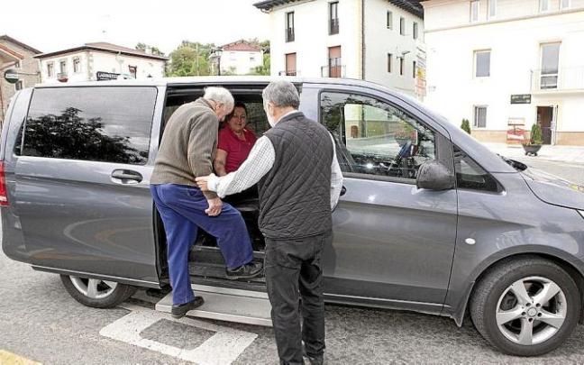 Un taxista ayuda a subir a su vehículo a un vecino de un pueblo alavés. Foto: Pilar Barco