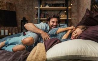 Una mujer ríe y se protege mientras su pareja le hace cosquillas. Una mujer ríe y se protege mientras su pareja le hace cosquillas.