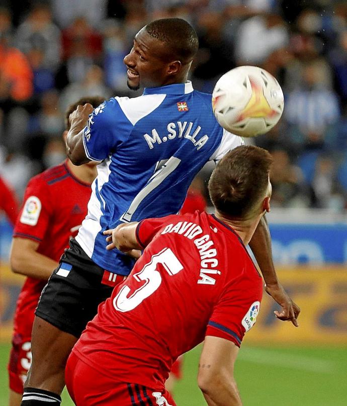 Sylla, que estrenó titularidad el pasado sábado en el derbi, luchar por un balón aéreo con el central navarro David García. Foto: Efe