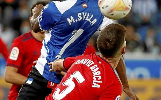 Sylla, que estrenó titularidad el pasado sábado en el derbi, luchar por un balón aéreo con el central navarro David García. Foto: Efe