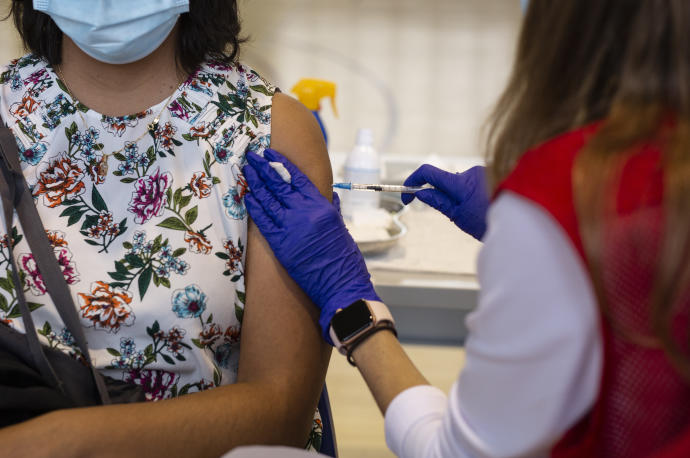 Una voluntaria de Cruz Roja administra una dosis de la vacuna.