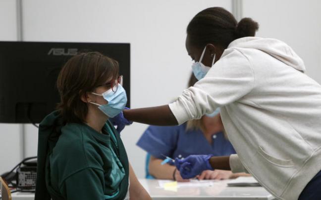Una enfermera pone la vacuna a un joven.