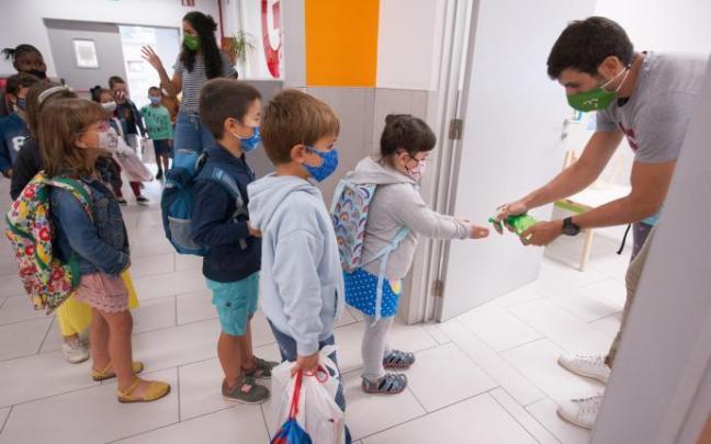 Un profesor echando gel en las manos de un alumno Foto: J.M.Martínez
