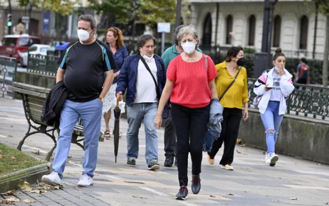 Personas paseando con mascarilla por una calle. Personas paseando con mascarilla por una calle.
