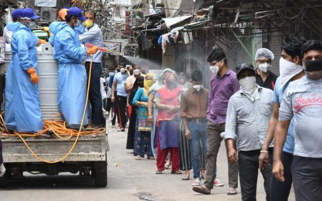 Desinfectan a ciudadanos antes de acceder a un centro en el que se realizan test de coronavirus en Nueva Delhi.