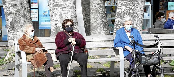 Personas mayores sentadas en un banco de Vitoria, compartiendo un rato al sol. Foto: Alex Larretxi