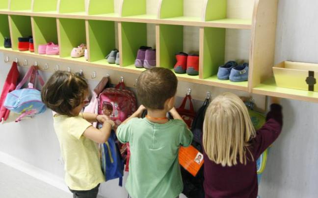 Tres niños se preparan antes de una clase en una ikastola.