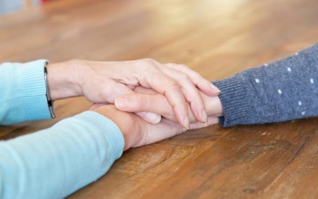 Una persona mayor sostiene la mano de su hija.