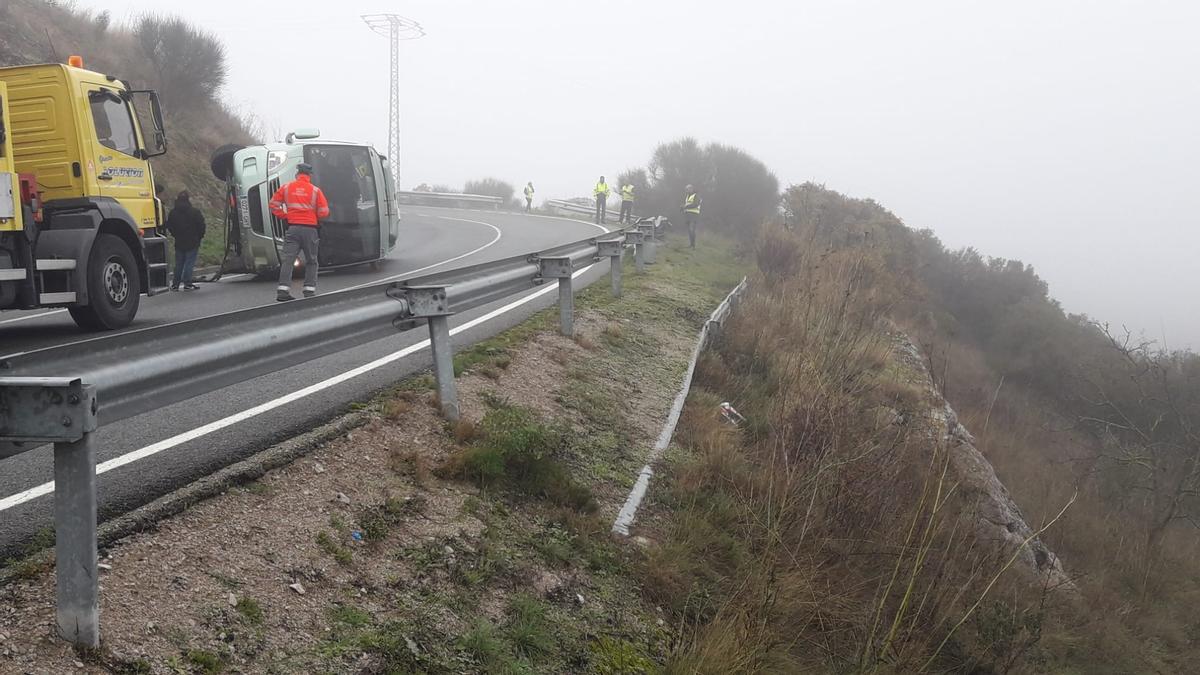 A la izquierda, el microbús volcado.