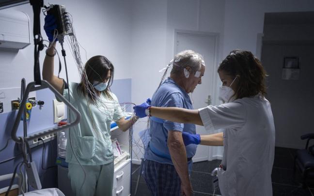 La neurofisióloga Rocío Veredas y la enfermera Irantzu Zahino preparan al paciente Luis Bezunartea para hacerle un estudio de sueño en el HUN.