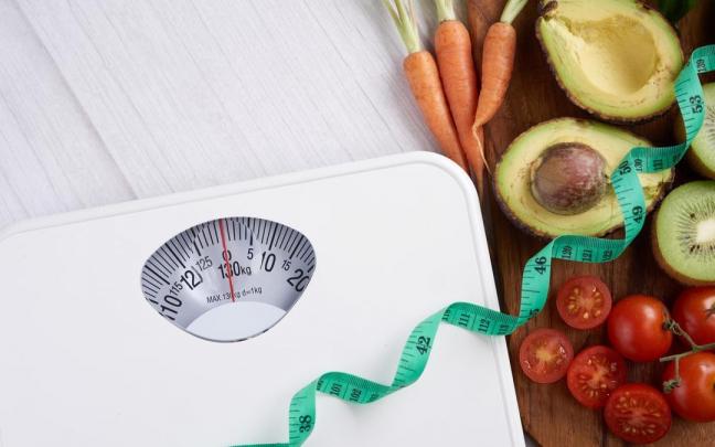 Una báscula y una cinta métrica junto a alimentos saludables. Una báscula y una cinta métrica junto a alimentos saludables.