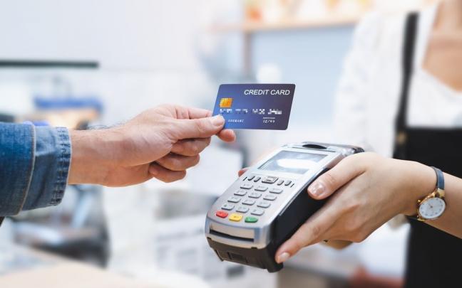 Una persona pagando con tarjeta en un dat&aacute;fono de un comercio.