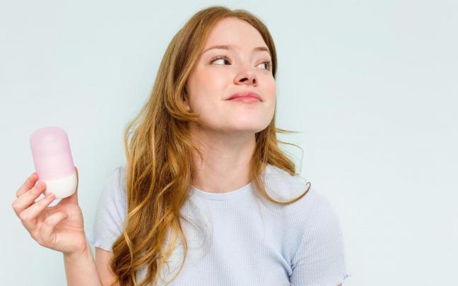 Una chica sujeta un bote de desodorante.