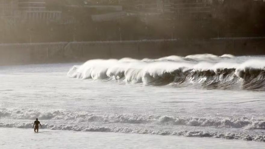 Una persona se mete en el agua en una jornada de aviso amarillo por mala mar