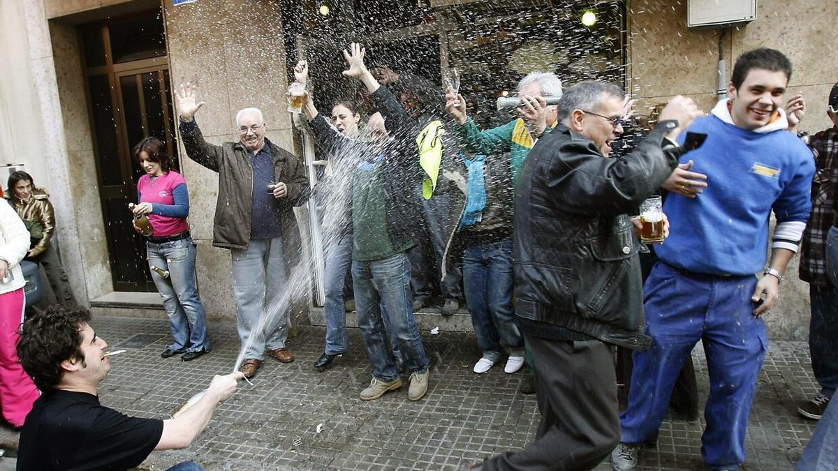 Un grupo de personas celebran junto a un bar que les ha tocado la Lotería.