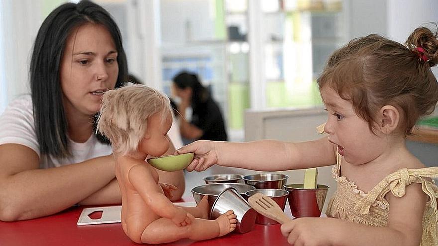 Una niña juega a dar de comer a una muñeca en la escuela de Azpilagaña. | FOTO: O.MONTERO