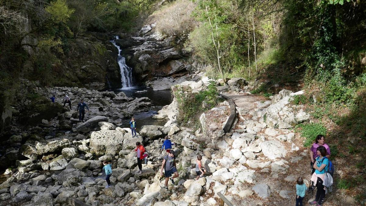 Visitantes aprovechan el buen tiempo para disfrutar de la cascada de Ixkier, en Mugiro, junto a la vía verde del Plazaola.