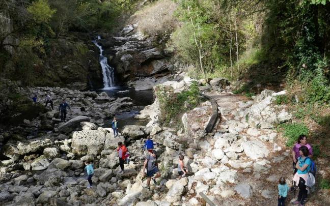 Visitantes aprovechan el buen tiempo para disfrutar de la cascada de Ixkier, en Mugiro, junto a la vía verde del Plazaola.