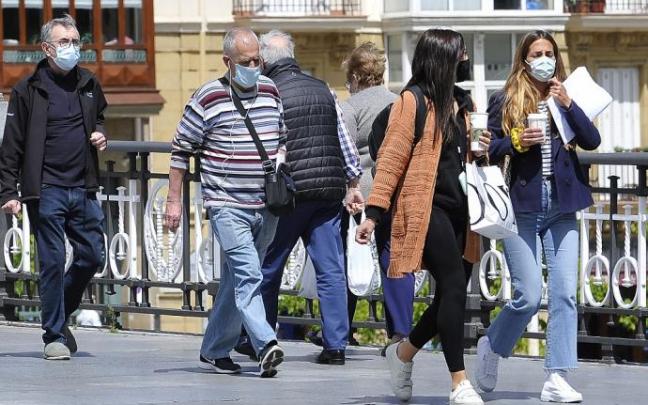 Gente paseando por la calle con mascarilla.