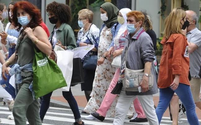 Varias personas andando por la calle con mascarilla.