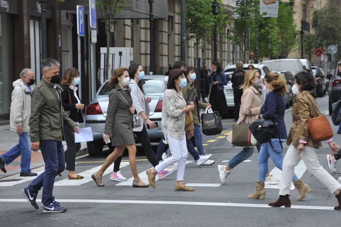 Gente paseando por la calle con mascarilla.