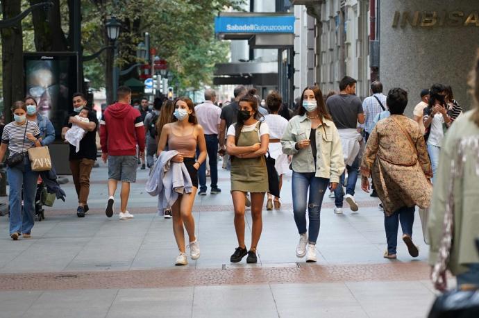 Gente paseando por la calle con mascarilla.