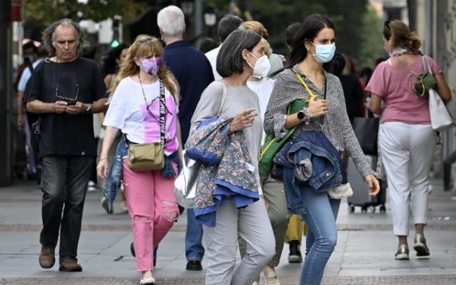 Varias personas andando por la calle con mascarilla.