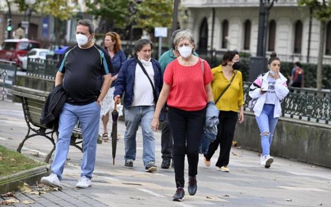 Varias personas caminan por la calle con mascarilla.