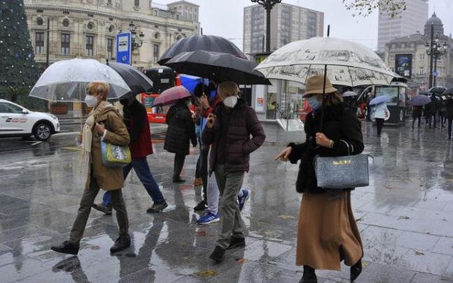 Varias personas caminan bajo la lluvia con paraguas. Varias personas caminan bajo la lluvia con paraguas.