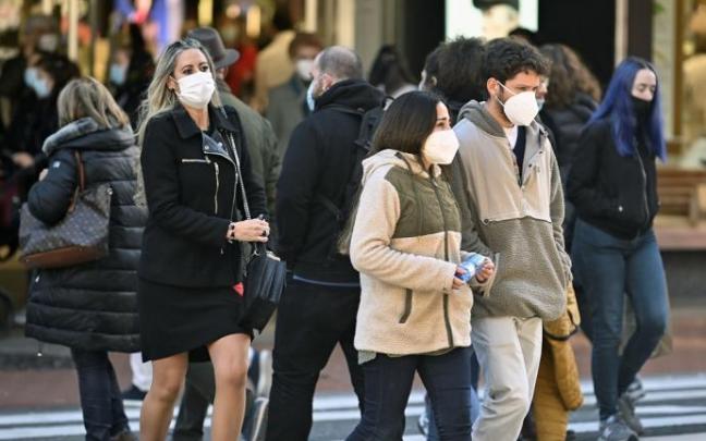 Gente paseando por la calle con mascarilla.