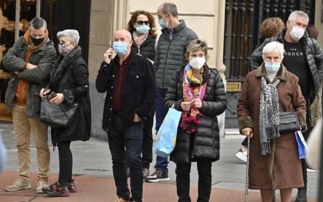 Varias personas paseando por la calle con mascarilla.
