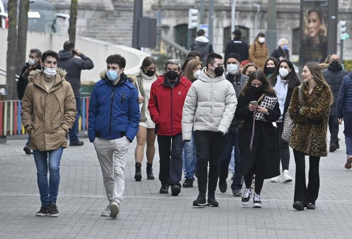 Varias personas pasean por la calle con mascarilla.