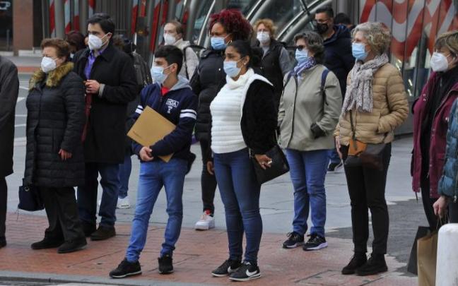 Gente paseando por la calle con mascarilla.