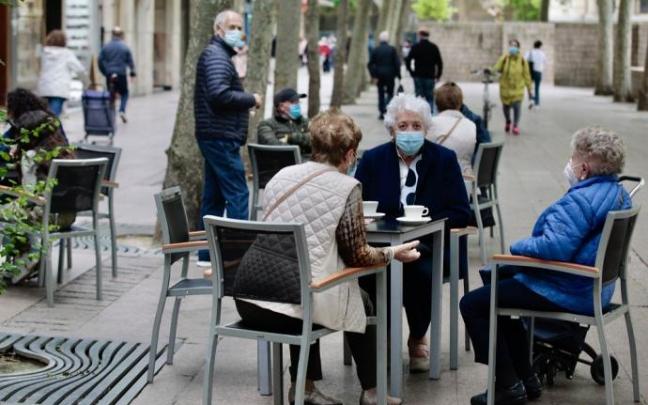 Varias personas sentadas en la terraza de un bar con mascarilla.