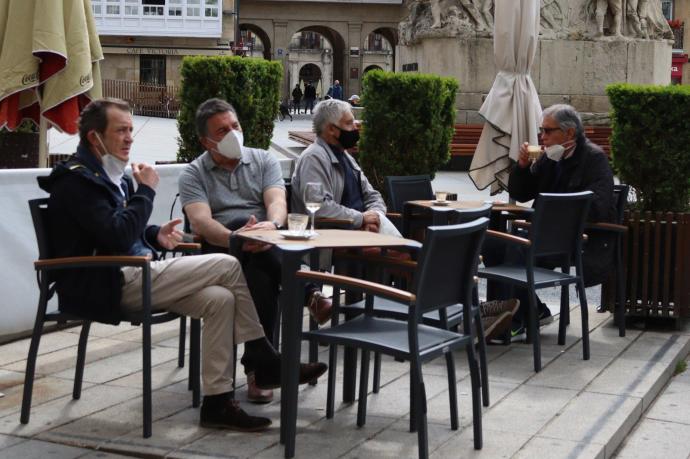 Personas sentadas en la terraza de un bar con mascarilla
