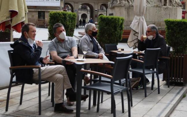 Personas sentadas en la terraza de un bar con mascarilla