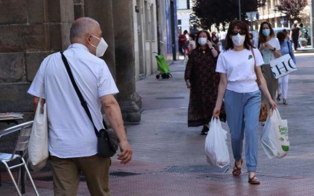 Personas andando por la calle con mascarilla.