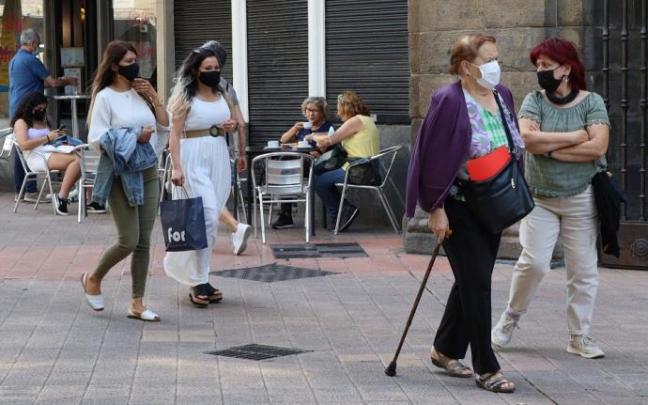 Personas andando por la calle con mascarilla.
