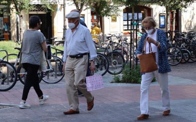 Personas andando por la calle con mascarilla.