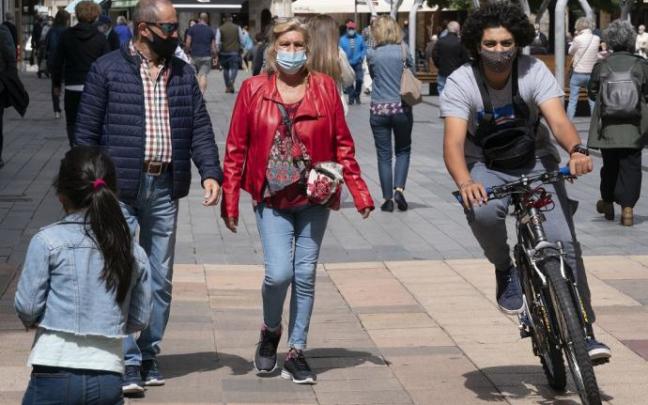 Personas andando por la calle con mascarilla.