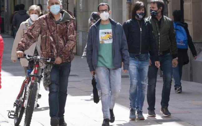 Personas andando por la calle con mascarilla.