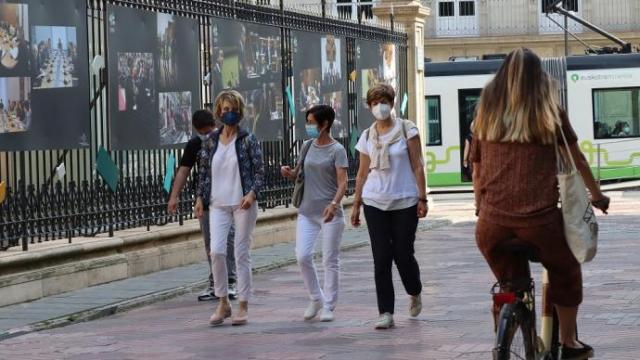 Varias personas paseando por la calle con mascarilla.