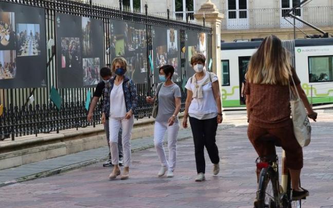 Varias personas paseando por la calle con mascarilla.