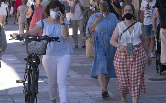 Varias personas andando por la calle con mascarilla.